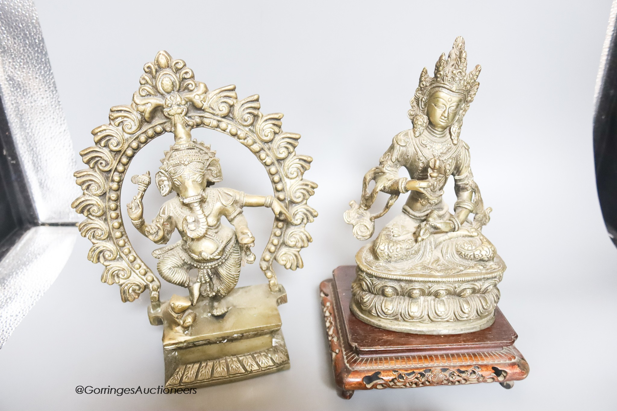 Two reproduction brass figures of Indian deities, a bell, a carved stand and a plaster plaque, tallest 26cm